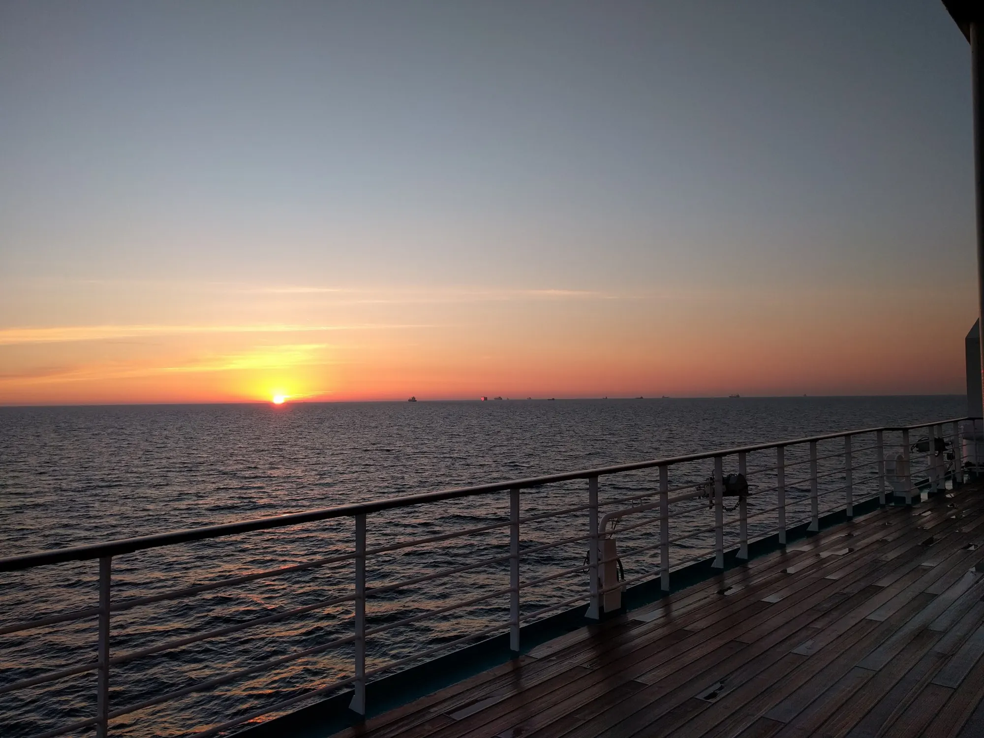 Sunset over the ocean from a cruise ship deck railing